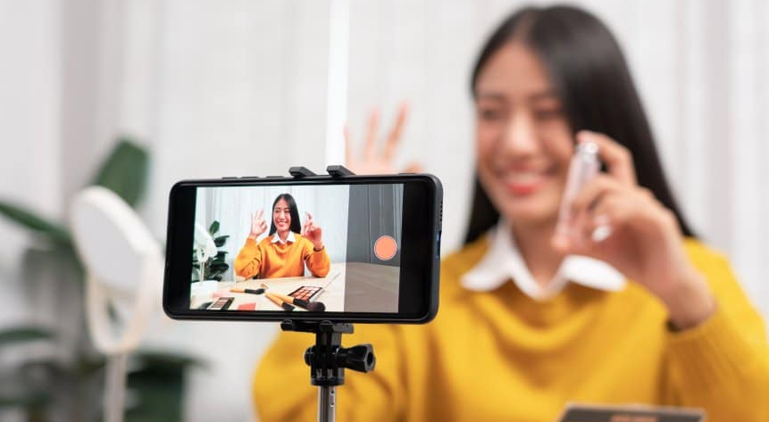 Smiling woman filming a product review on her phone, ideal for UGC creators or affiliate marketing campaigns.